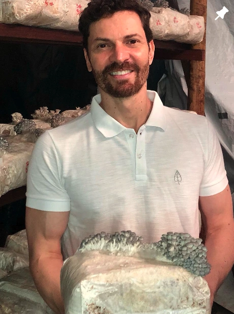 Ento sorrindo e segurando os cogumelos produzidos no próprio substrato